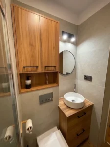 Łazienka w naturalnych kolorach z drewnem i białą umywalką