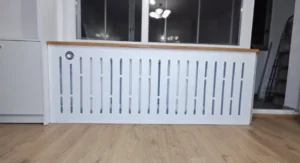 Szeroka zabudowa grzejnika pod oknem z frezowanym wzorem